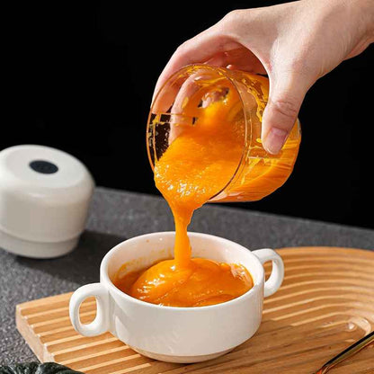 main versant du jus de mangue d'un hachoir électrique dans une tasse